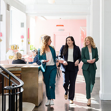 three young professional woman walking and talking through a lobby