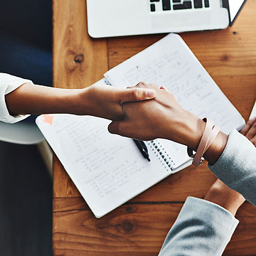 women shaking hands across a desk