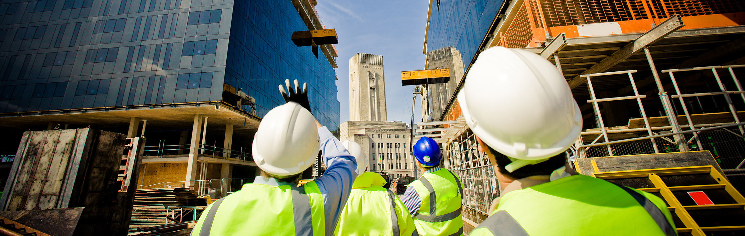 three construction workers in hard hats looking at a build site