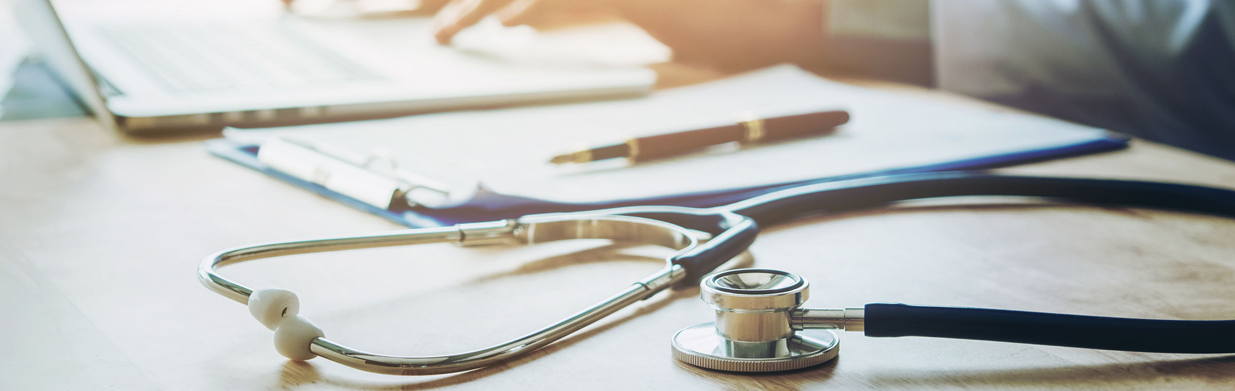 Doctor typing information on Laptop in Hospital office focus on Stethoscope