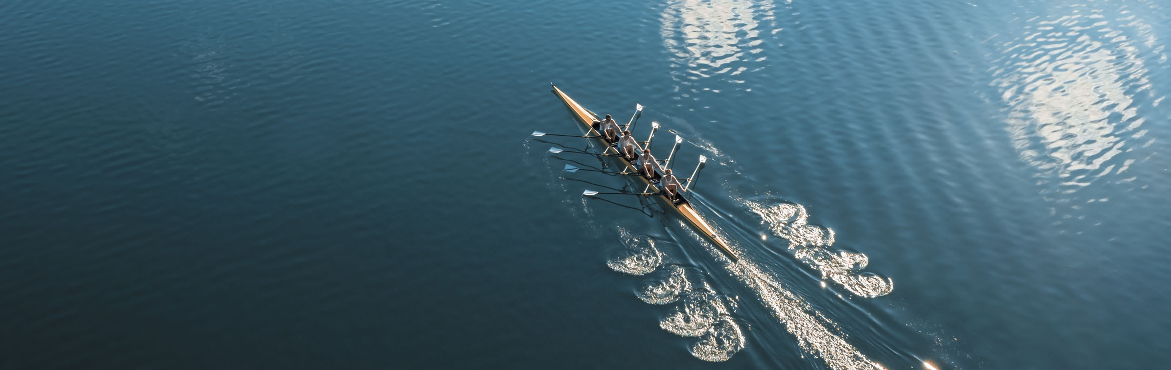 rowing team rowing across a blue lake