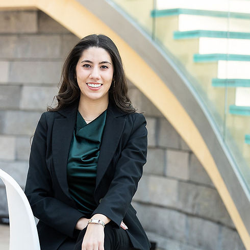 young professional woman sitting in front of a modern staircase and gray brick wall