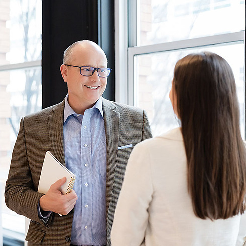 professional man speaking to a young woman with her back to the camera