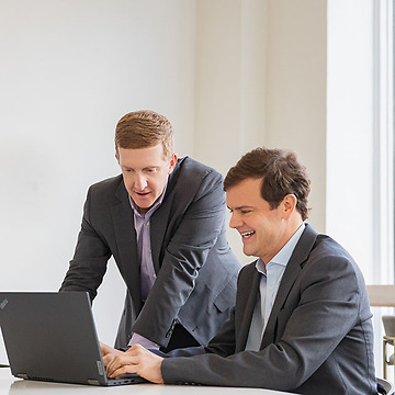 two professional men in suits looking at a laptop